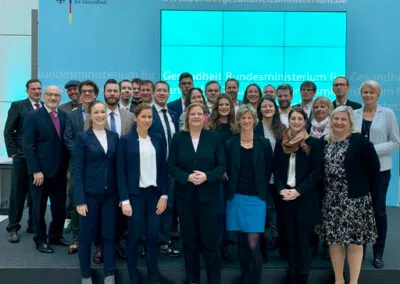 Gruppenbild der Preisträger im Bundesministerium für Gesundheit vor einer Videowand